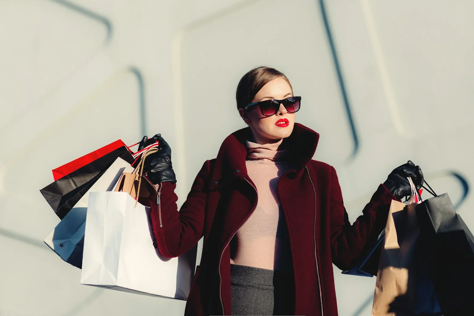 A woman in a burgundy coat holds several shopping bags
