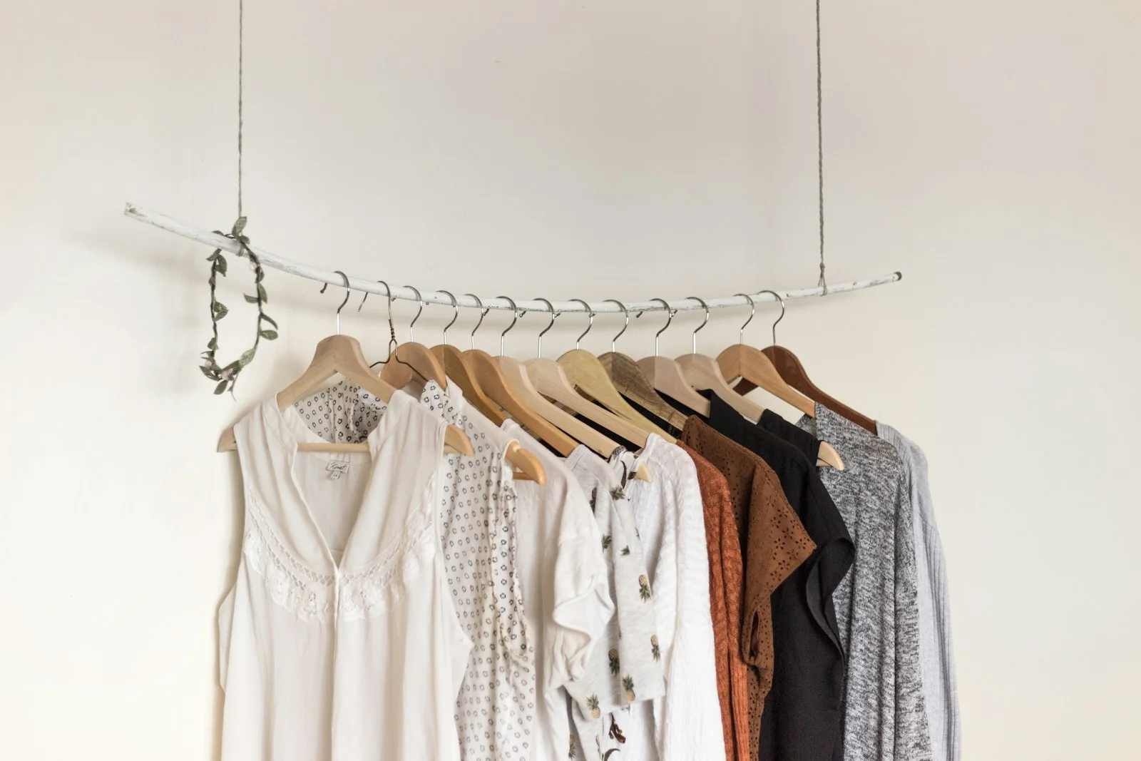 Light-coloured garments on wooden hangers form a compact clothing rail