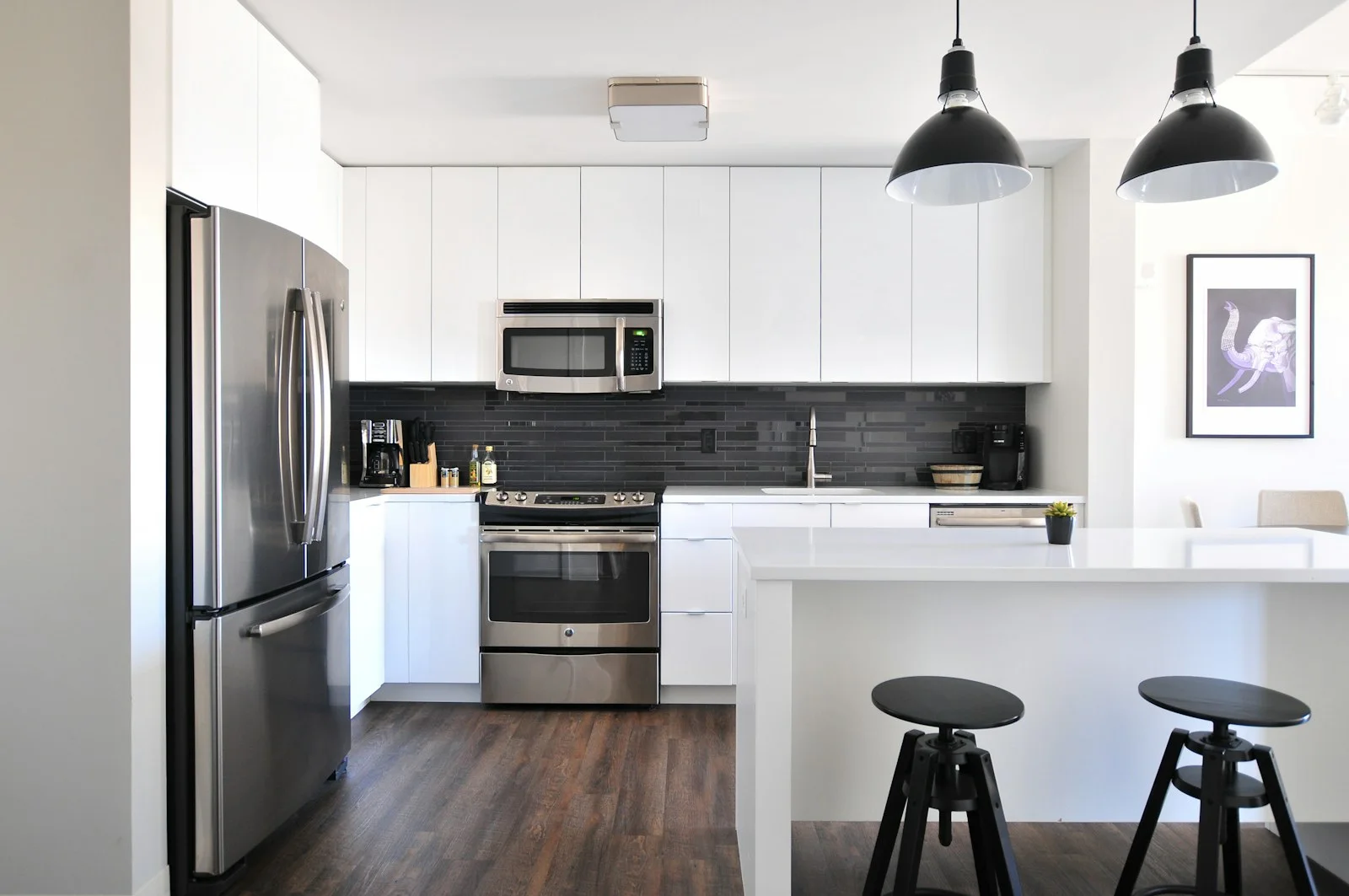 A bright kitchen with pendant lights, white cabinetry and breakfast bar stools